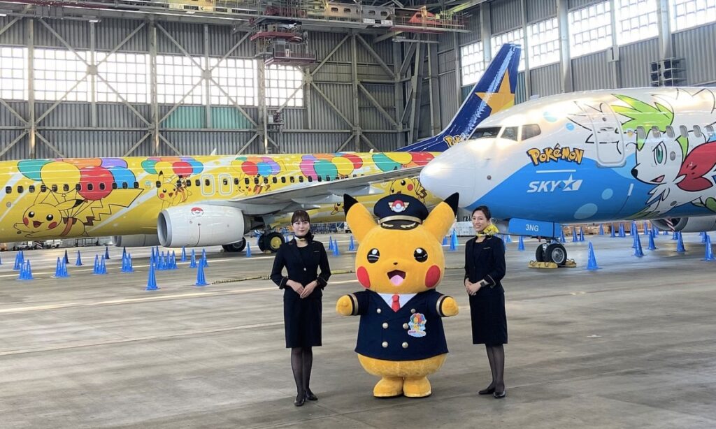 airhostesses with pikachu effigy posing in front of pikachu jet
